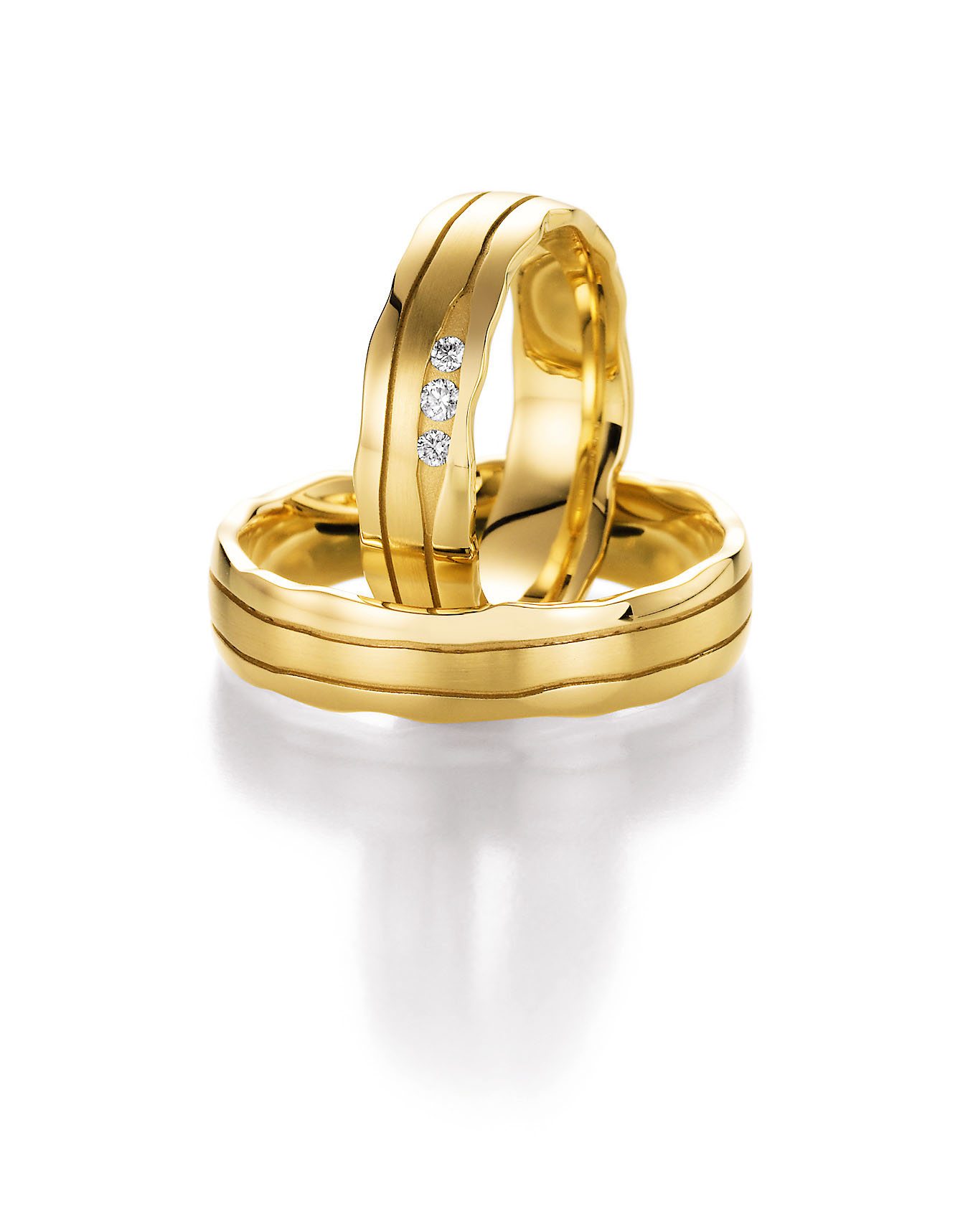 Elegante Trauringe aus Gelbgold mit sanft geschwungener Form und feinen Linien. Der Damenring ist mit drei Brillanten verziert und verleiht dem Ringset eine edle, harmonische Ausstrahlung.