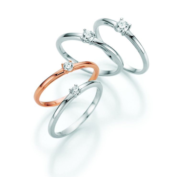 Vier elegante Solitärringe in Weißgold und Roségold mit jeweils einem funkelnden Diamanten in Krappenfassung. Die zeitlosen Ringe präsentieren klassische Schmuckdesigns für Verlobung, besondere Anlässe oder den täglichen Stil.