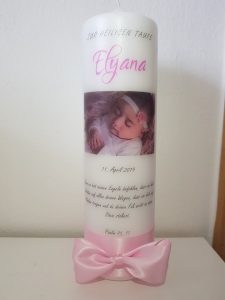 Taufkerze mit Foto eines schlafenden Babys, rosa Schleife und dem Namen 'Elyana' sowie weiteren Texten.