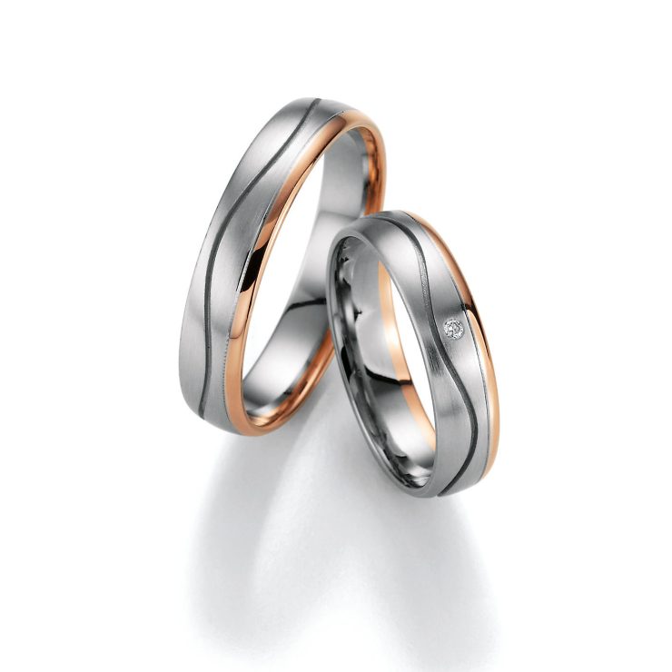 Modernes Partnerring-Set in Silber- und Roségoldoptik mit sanft geschwungenem Design. Die matte silberfarbene Oberfläche wird durch roségoldfarbene Akzente an den Seiten elegant ergänzt. Einer der Ringe ist mit einem funkelnden klaren Zirkonia besetzt und verleiht dem Set eine edle, zeitlose Ausstrahlung. Ideal als Trau-, Verlobungs- oder Freundschaftsringe.