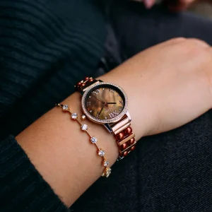 Jacques du Manoir Damenuhr mit roségoldenem Gehäuse, Perlmuttzifferblatt und dekorativem Armband am Handgelenk getragen
