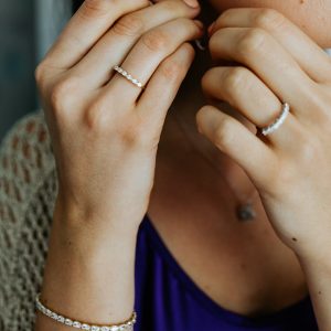 Person trägt schmale Ringe und ein passendes Armband mit funkelnden Zirkonia sowie eine Halskette.