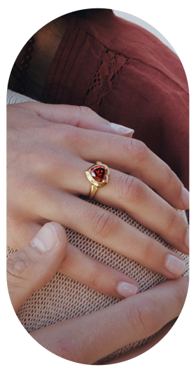 Stimmungsvolle Lifestyle-Aufnahme eines eleganten Rings in Goldoptik mit einem herzförmigen, facettierten Schmuckstein in intensivem Rubinrot. Das Schmuckstück wird an der Hand getragen und setzt einen romantischen Akzent. Die glänzende Fassung umrahmt den roten Herzstein harmonisch und sorgt für ein edles Erscheinungsbild. Das warme Licht und die natürliche Tragesituation unterstreichen die emotionale und feminine Ausstrahlung des Rings.