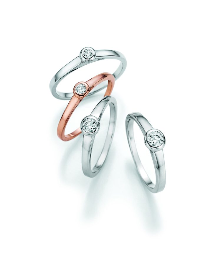 Filigrane Solitärringe in Weißgold und Roségold mit zentral gefasstem Brillanten in eleganter Zargenfassung. Zeitlose Schmuckstücke mit puristischem Design und funkelnder Ausstrahlung für jeden Anlass.